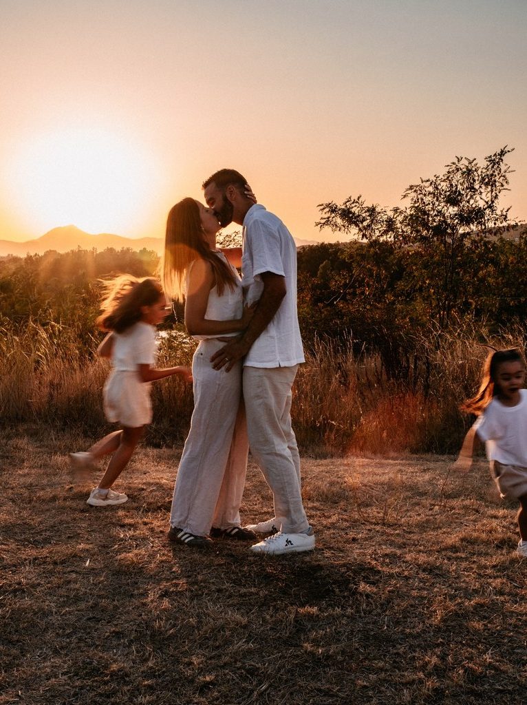 photo de couple qui s'embrasse au coucher de soleil avec les enfants qui courent et tuent dans le puy de dôme